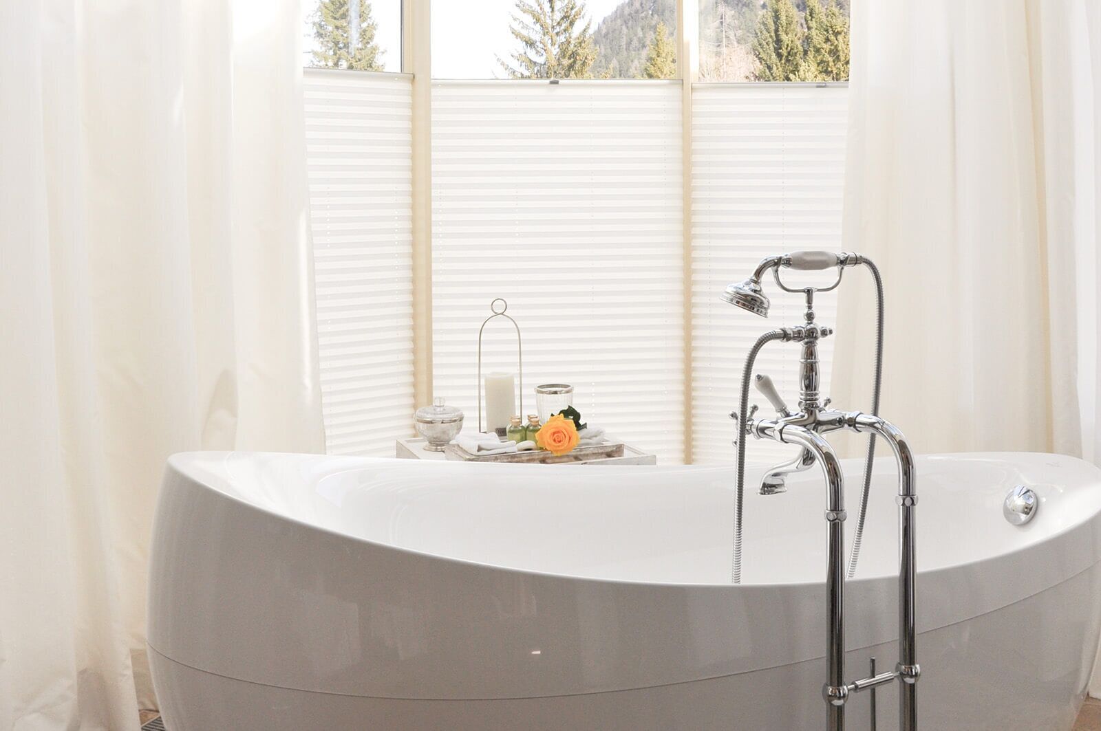A modern bathroom with a freestanding bathtub, a showerhead, and a window with blinds.