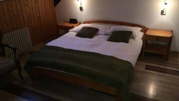 A wooden-framed bed with a green blanket, two bedside tables, and wall-mounted lights.