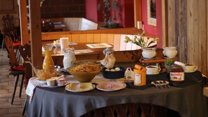 A breakfast table set with various dishes, including a bowl of cereal, a pitcher of orange juice, and several cups and bowls. - Historic Hotel Steinbock (Gsteigwiler)