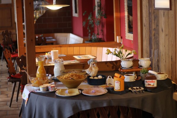 Uma mesa de café da manhã posta com diversos pratos, incluindo uma tigela de cereal, um jarro de suco de laranja e algumas xícaras e tigelas.