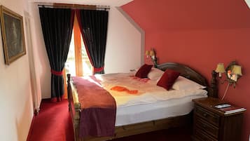 Un dormitorio con cama de madera, paredes rojas, alfombra roja, mesita de noche con lámpara y ventana con cortinas.