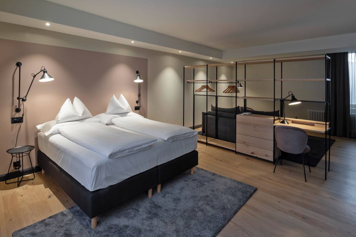 Une chambre moderne avec un grand lit, des lampes de chevet, un bureau et une armoire.