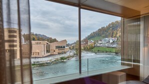 A modern interior with a large window overlooking a river and buildings.