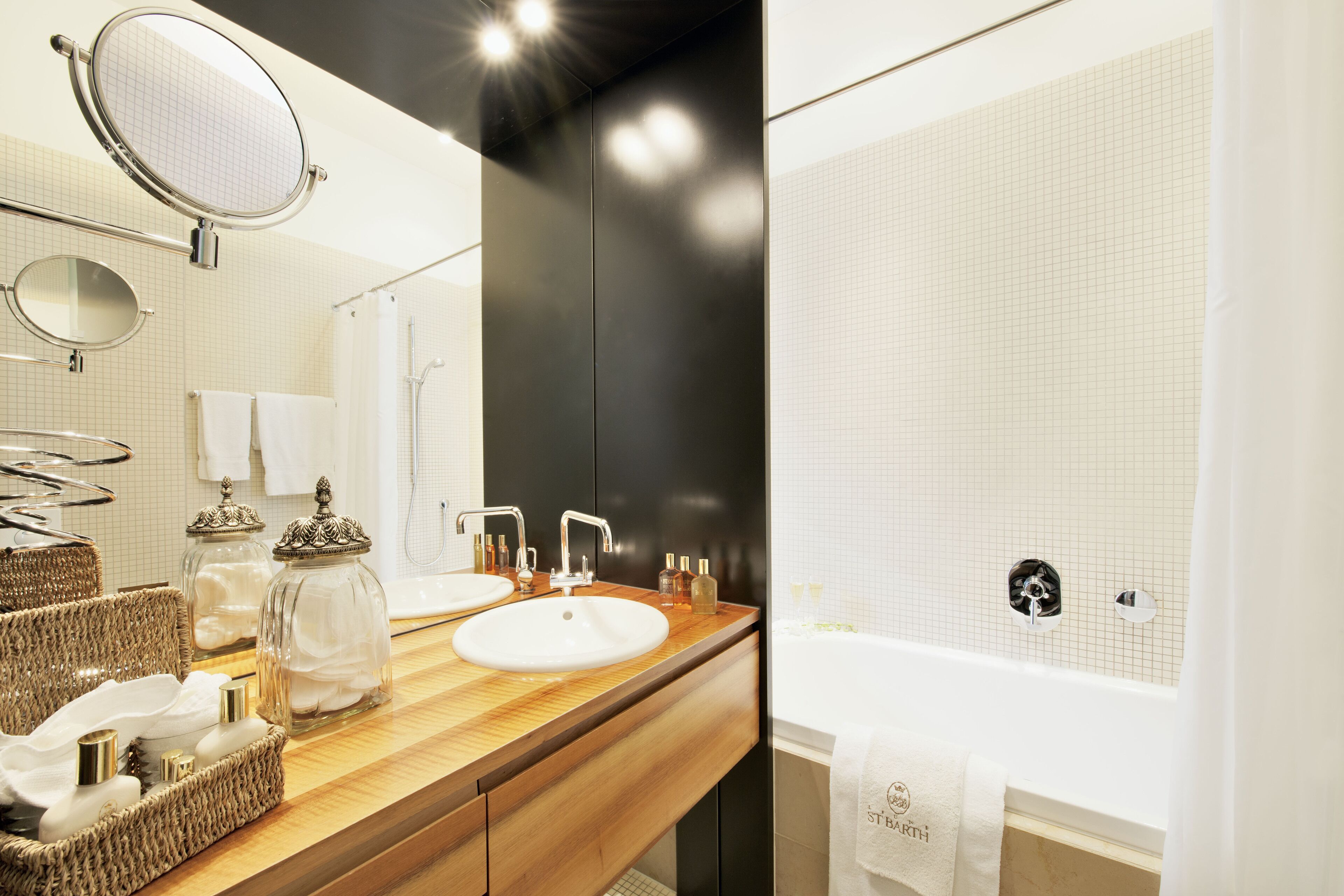 Une salle de bain moderne avec un meuble-lavabo en bois, deux vasques, un grand miroir et une baignoire.