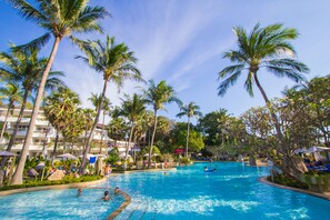 A large swimming pool surrounded by palm trees and hotel buildings. - Thavorn Palm Beach Resort Phuket (Karon)