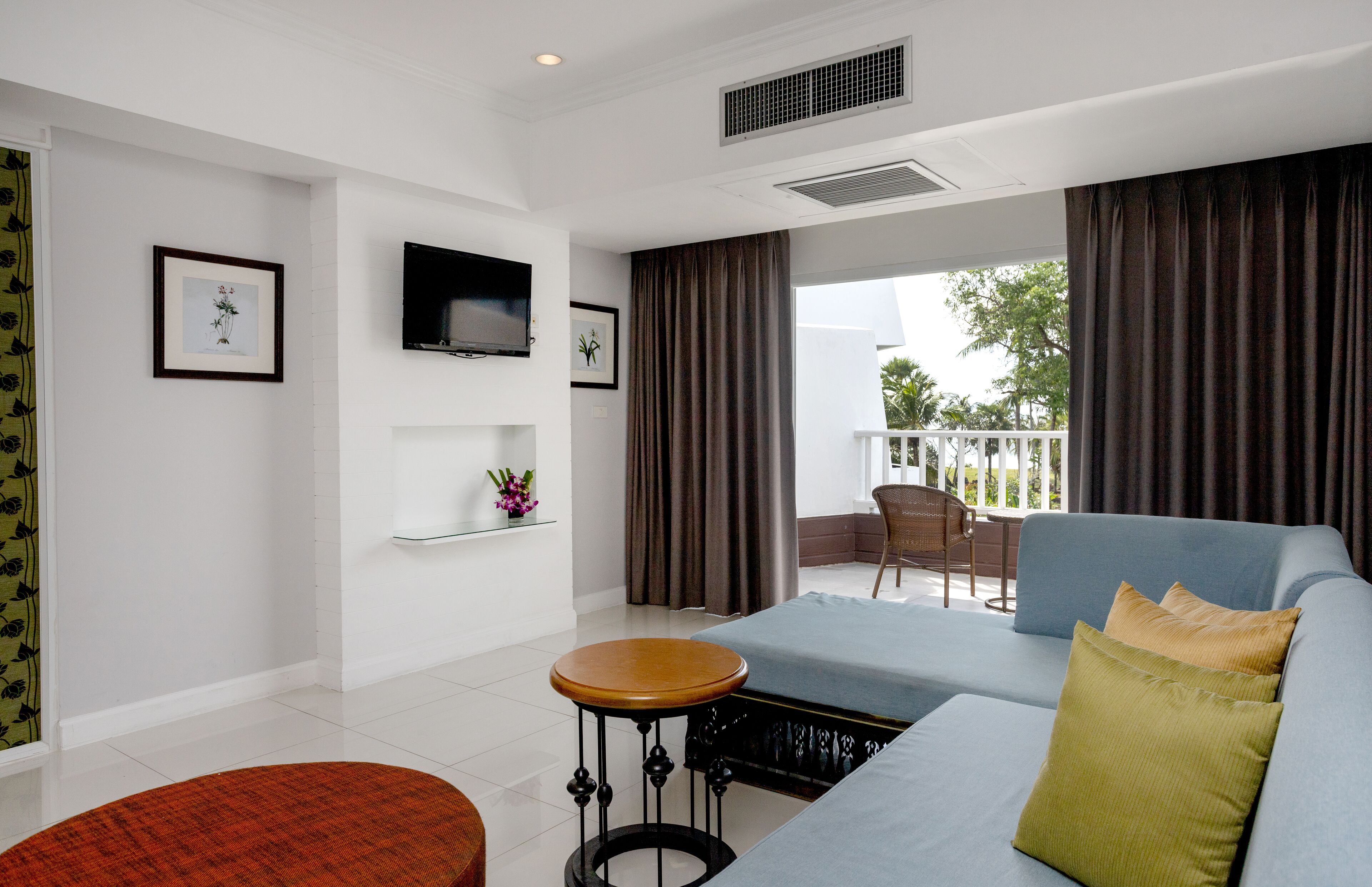 A modern living room with a sofa, a small round table, and a TV mounted on the wall.