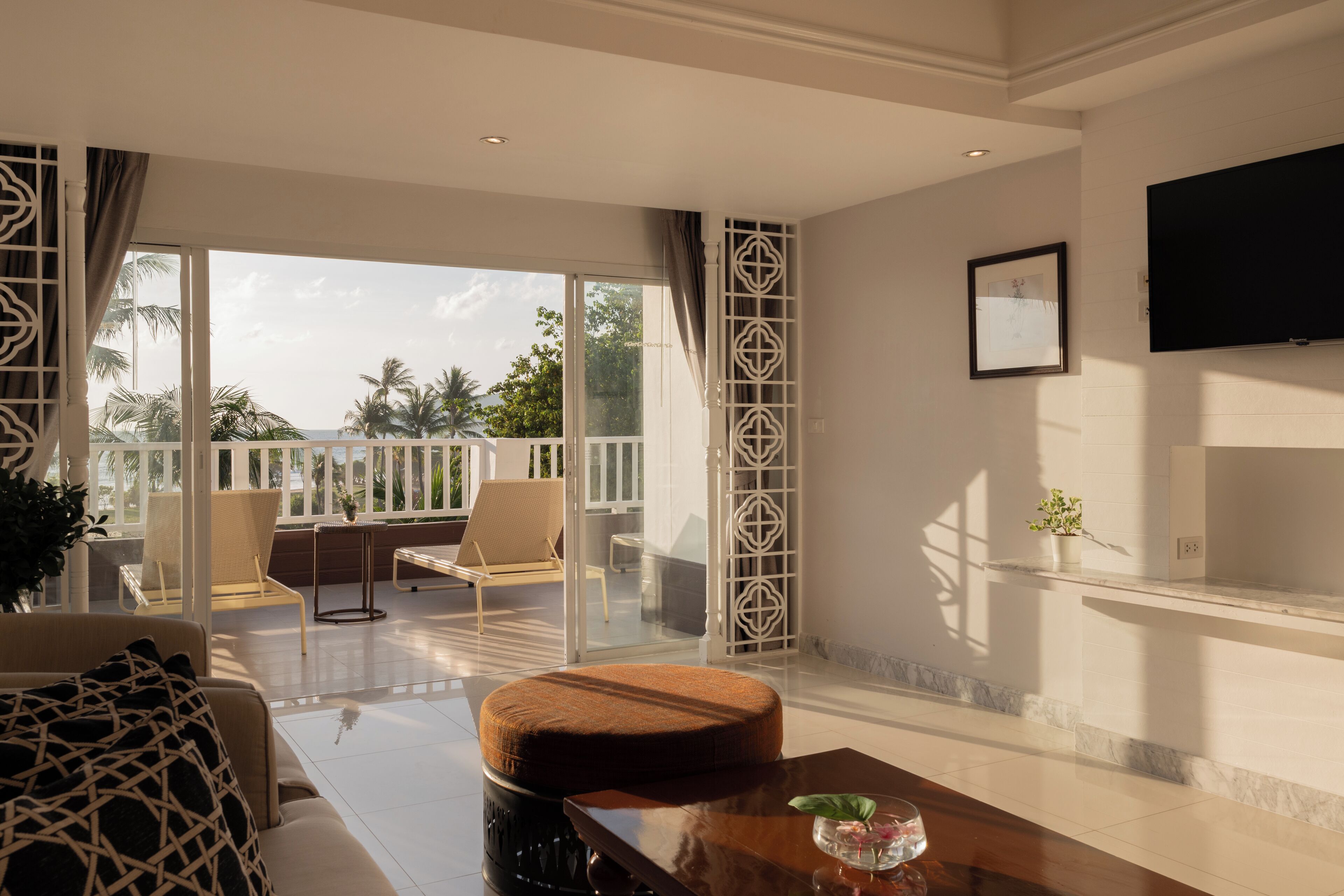 Una camera d'albergo moderna con un balcone, un divano, un tavolino da caffè e una TV a parete.
