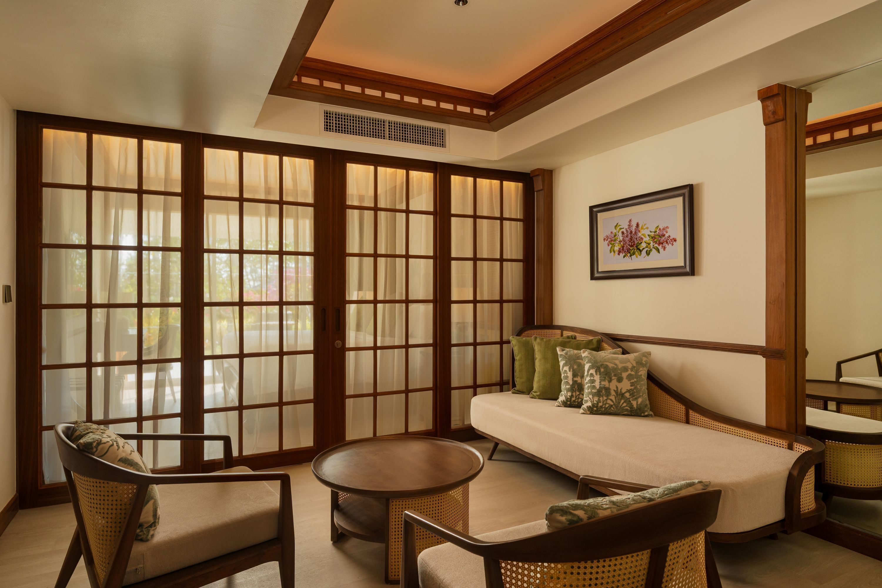 A traditional room with tatami flooring, a low wooden bed, a cushioned bench, and a round table.
