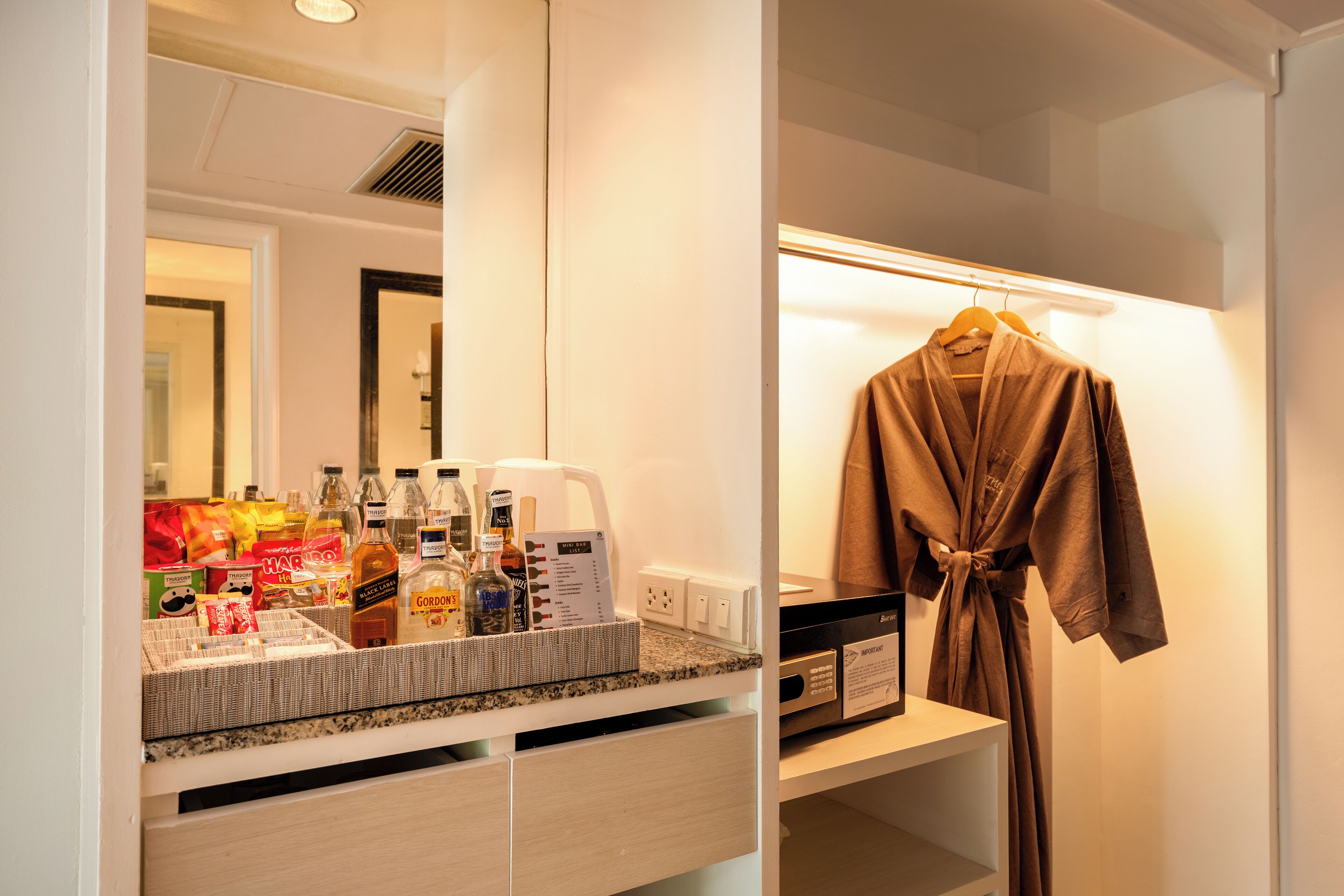 A hotel bathroom with a mirror, a robe hanging on a rack, and toiletries on the counter.