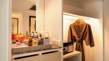 A hotel bathroom with a mirror, a robe hanging on a rack, and toiletries on the counter.