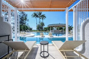 A poolside area with lounge chairs and a small round table, surrounded by a white pergola and decorative lattice. - Thavorn Palm Beach Resort Phuket (Karon)