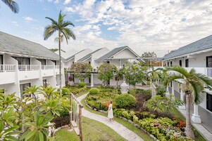 A resort with white buildings, a central garden, and a pathway.