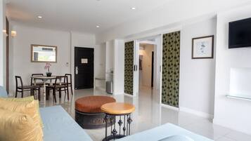 A modern living room with a sofa, ottoman, and dining area.