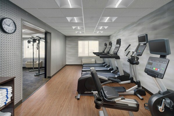 A gym with multiple treadmills, a stationary bike, and a wall clock.
