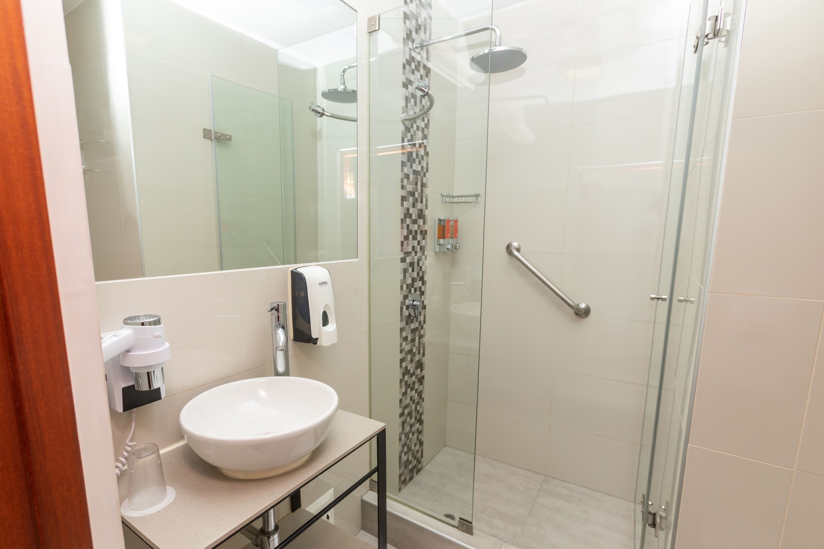 A modern bathroom with a glass-enclosed shower, a white sink, and a mirror.