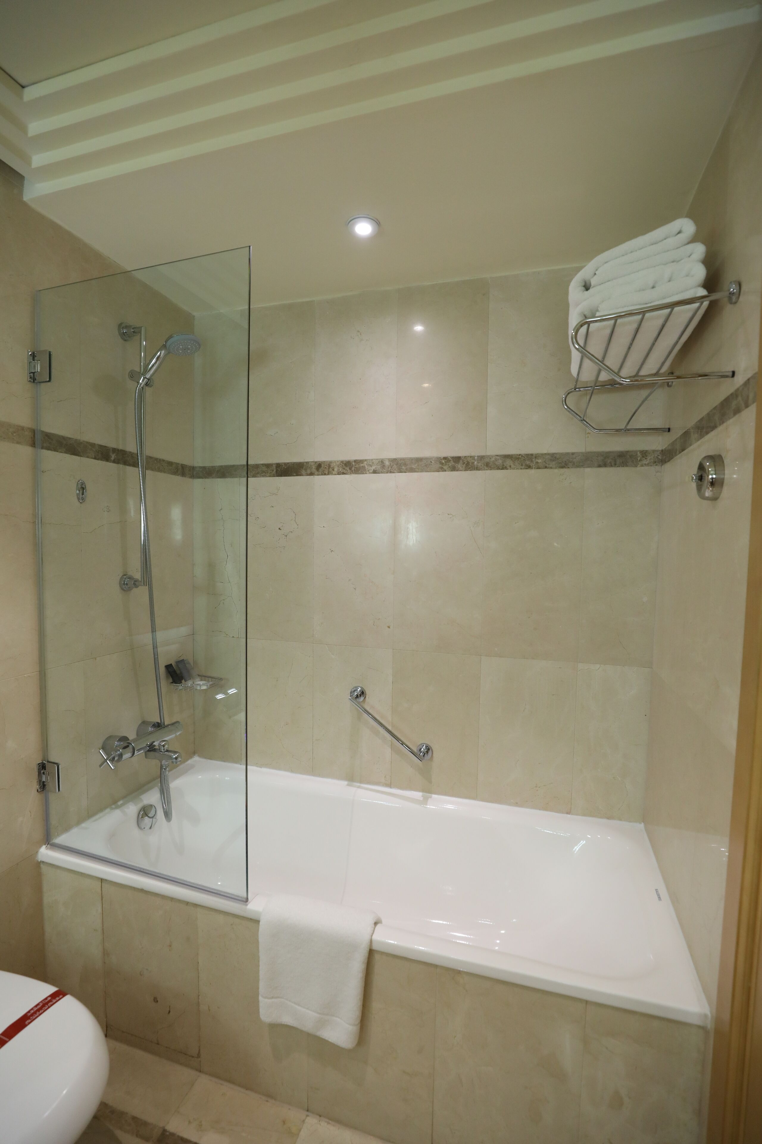 Un baño moderno con ducha envuelta en vidrio, una bañera blanca y un perchero para toallas.