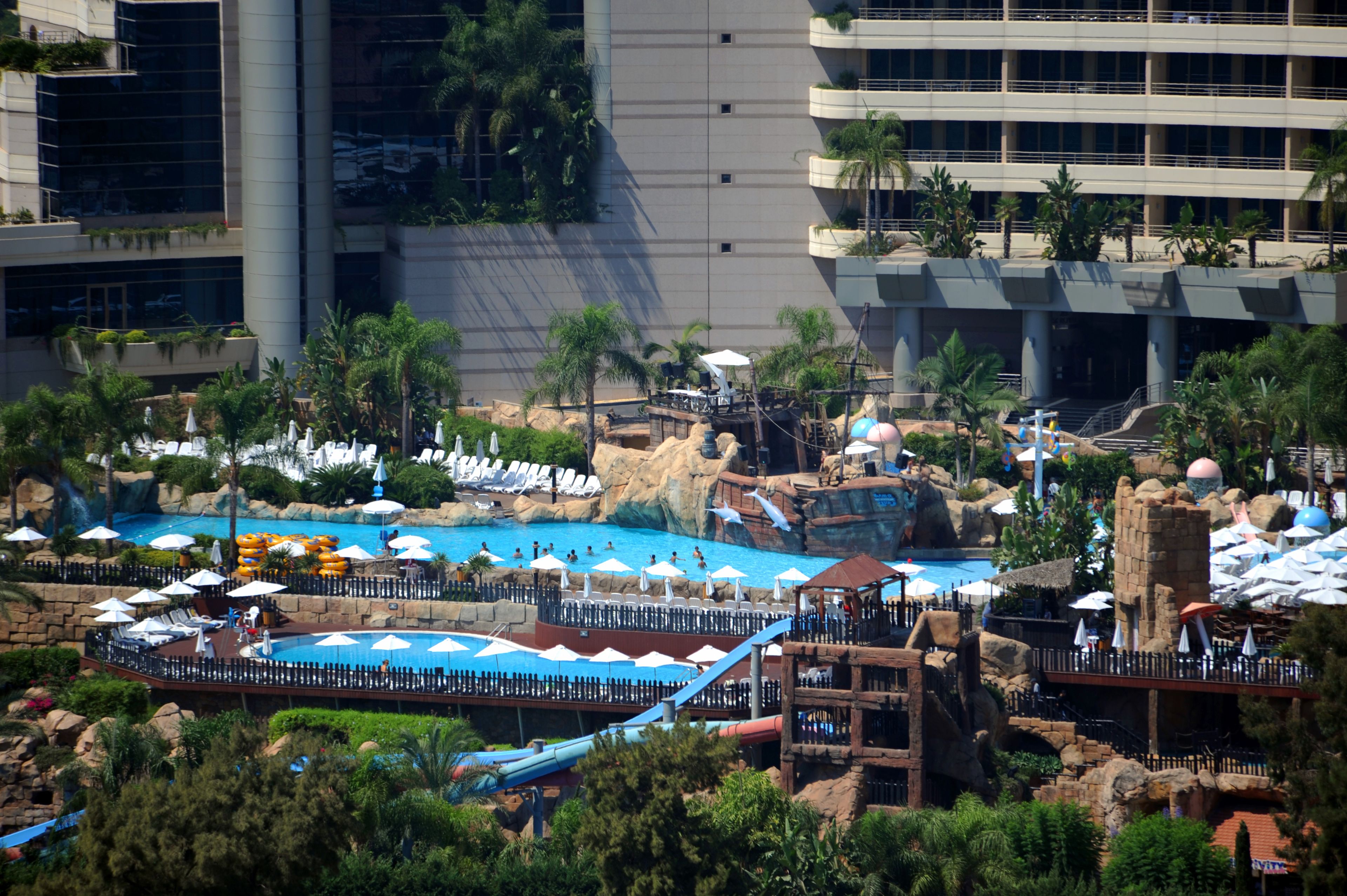 Un resort con una amplia zona de piscina, toboganes acuáticos y una formación rocosa.