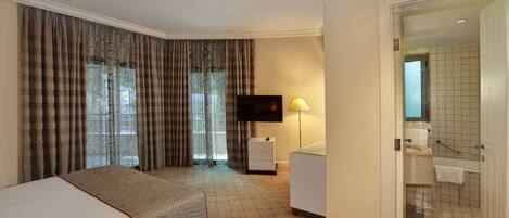Hotelkamer met een bed, een televisie, een nachtkastje, een lamp en een badkamer met douche en toilet.