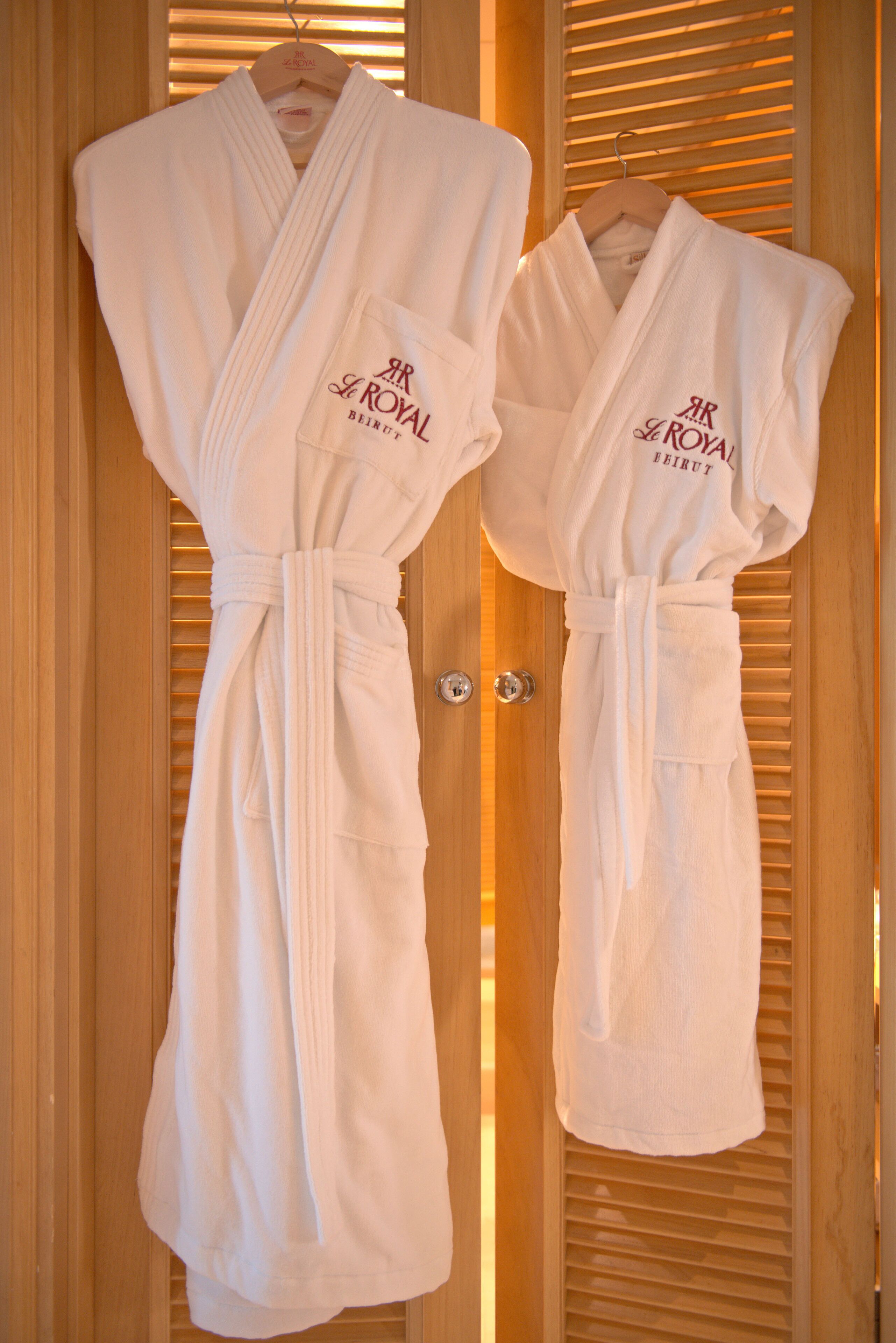 Two white robes with "AR ROYAL BEIRUT" text hanging on a wooden door.