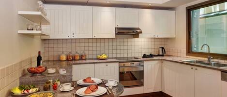 Una cocina moderna con armarios blancos, horno empotrado y un ventanal grande.
