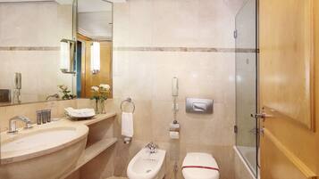 A modern bathroom with a large bathtub, a bidet, a toilet, and a vanity with a sink and mirror.