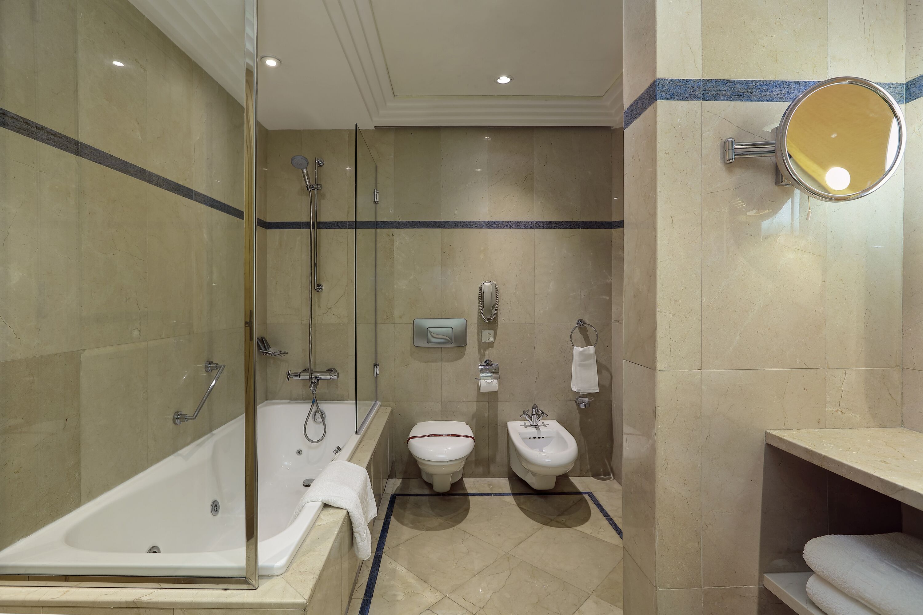 A modern bathroom with a glass-enclosed shower, a standalone bathtub, a toilet, and a bidet.