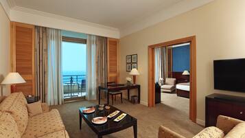 A hotel room with a balcony, a dining area, a TV, and a bed.