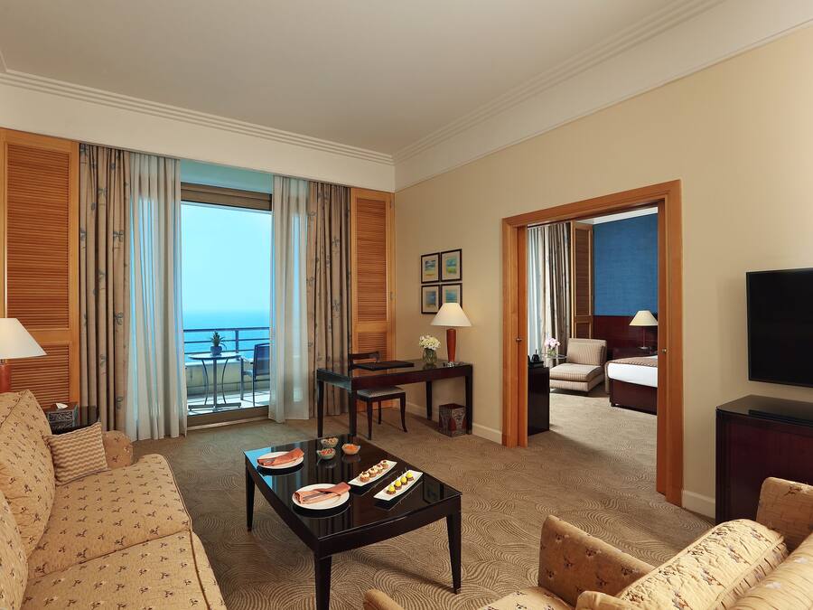 A hotel room with a balcony, a dining area, a TV, and a bed.