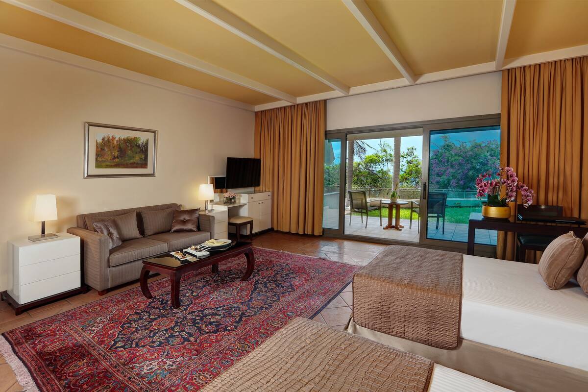 A spacious living room with a sofa, a coffee table, and a large window offering a view of the outdoors.