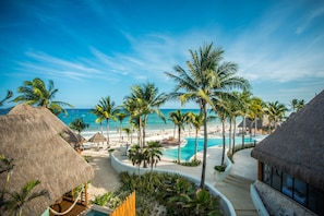 Een resort met een zwembad, palmbomen en een strand.
