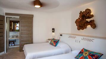 Habitación de hotel con dos camas, un armario de madera, un baño con lavamanos y un adorno en la pared.