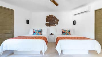 Habitación de hotel con dos camas, ventilador de techo, aire acondicionado y un adorno en la pared.