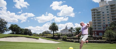 Campo de golf con un green cuidado, bunkers de arena y un edificio grande al fondo.