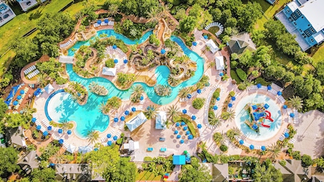 Vue aérienne d’un complexe hôtelier doté de plusieurs piscines, d’espaces de détente et de palmiers.