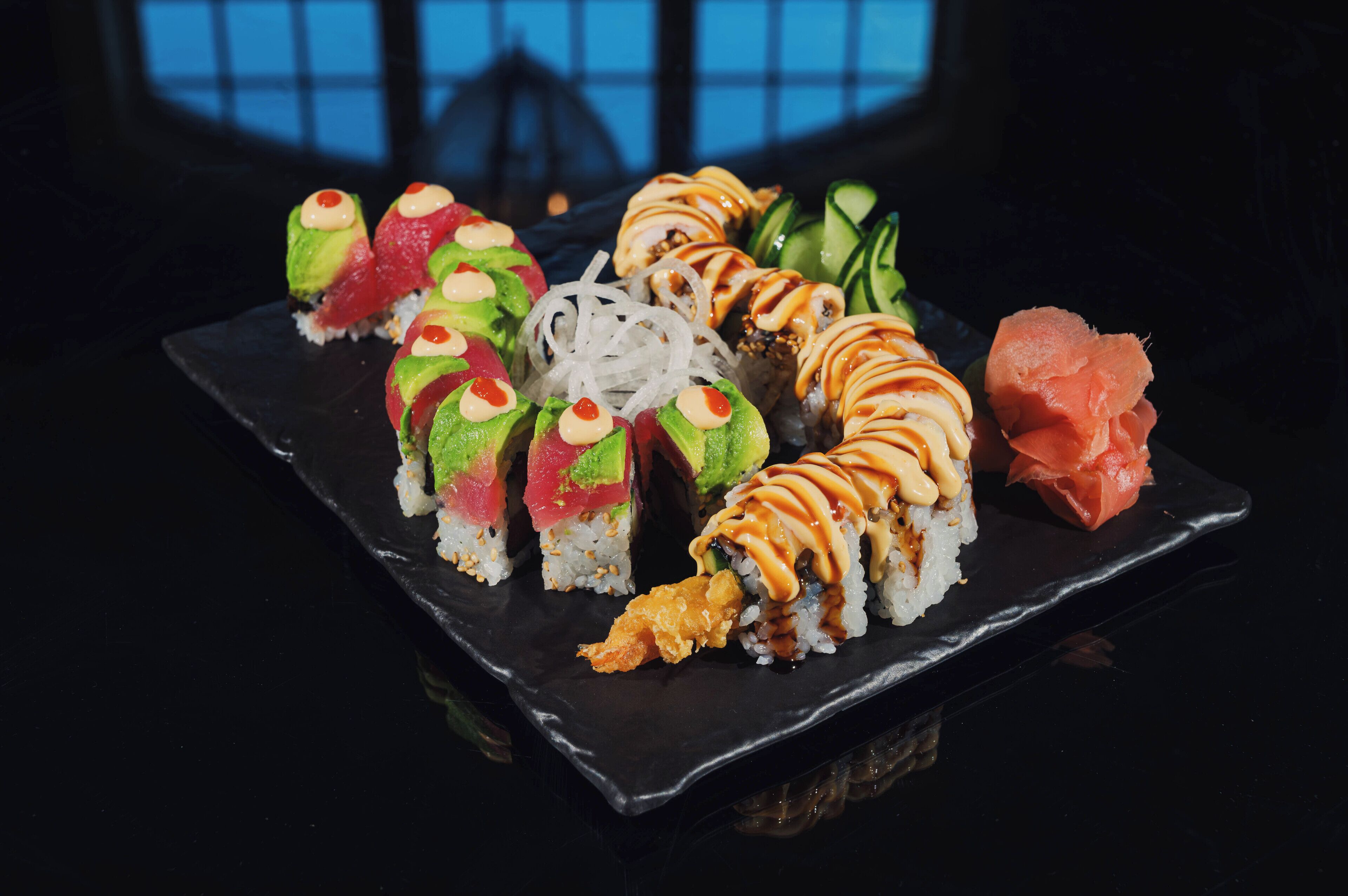 A variety of sushi on a black plate.