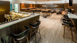 A modern restaurant with a bar area, wooden flooring, and a variety of seating options including bar stools and tables. - Kinzie Hotel (Chicago)