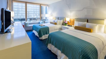 Habitación de hotel con dos camas, televisión, escritorio y un amplio ventanal con vistas a la ciudad.