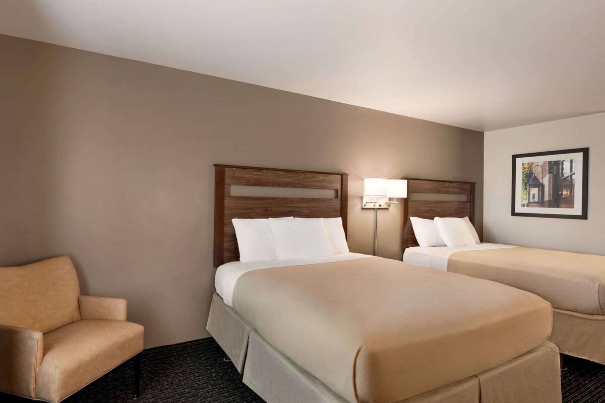 Une chambre d’hôtel avec deux lits, un canapé et une lampe.
