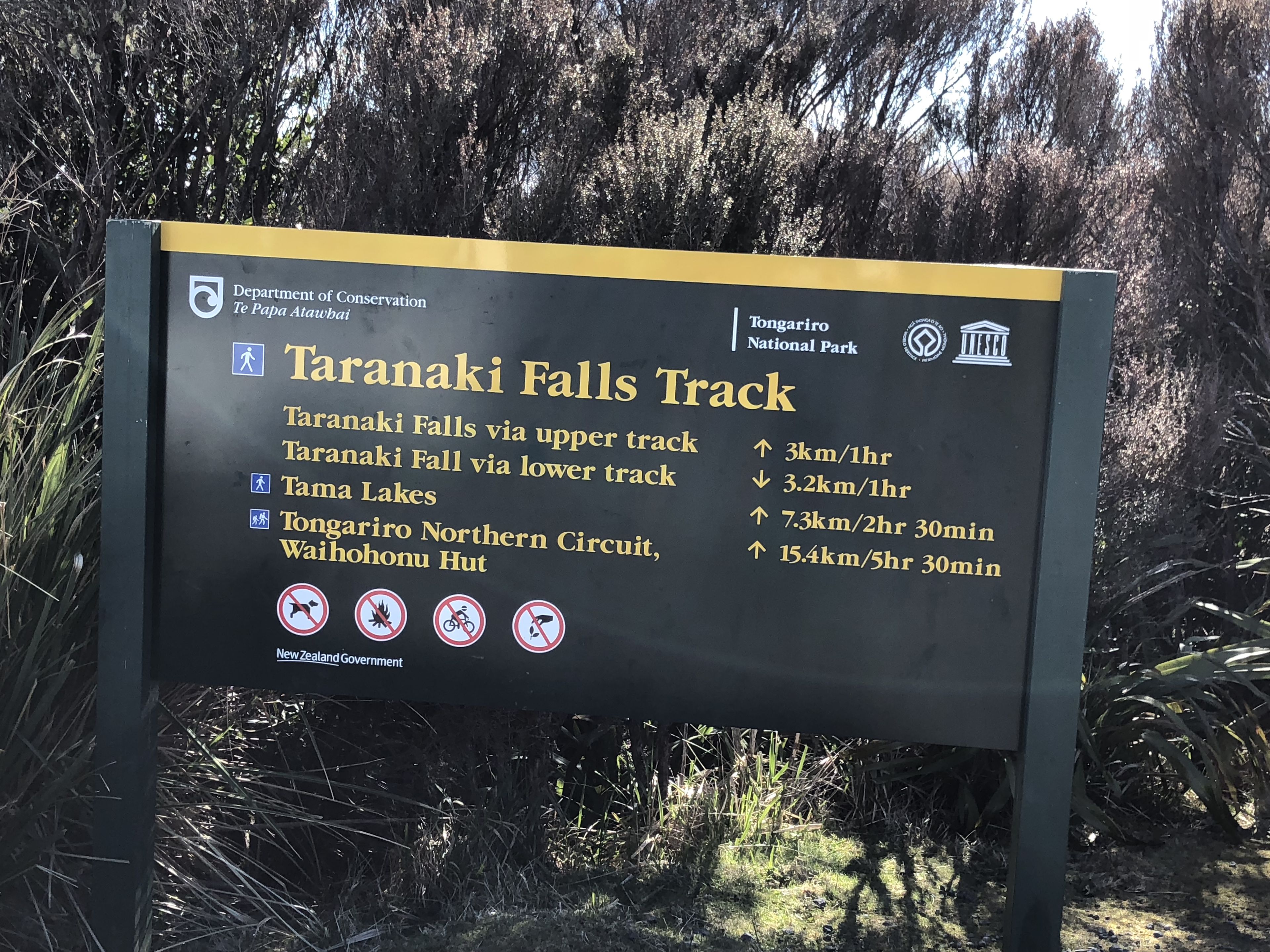 Señal del sendero Taranaki Falls con indicaciones y distancias a varios puntos de interés.