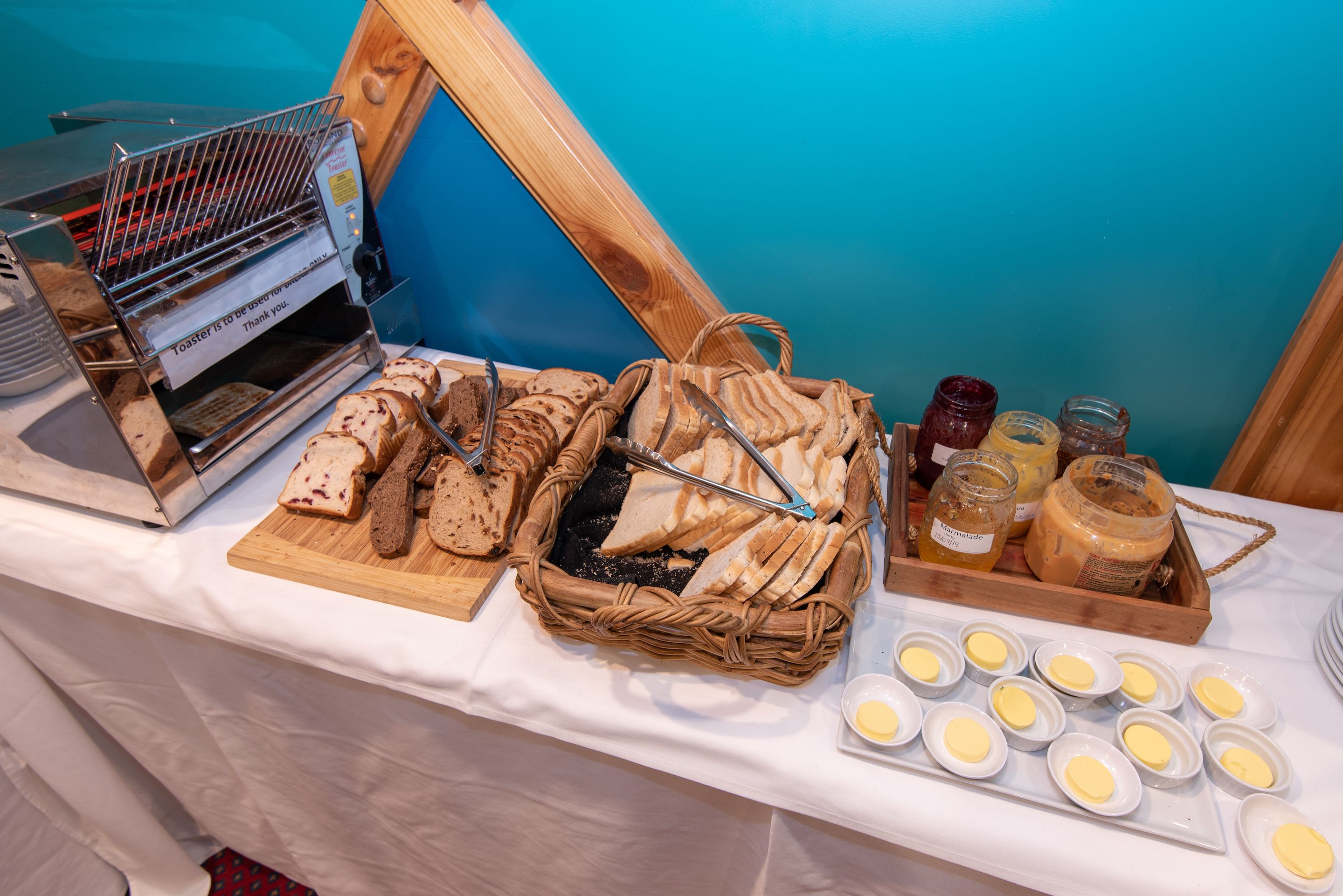 Una mesa de buffet con panes, mermeladas y mantequilla varios.
