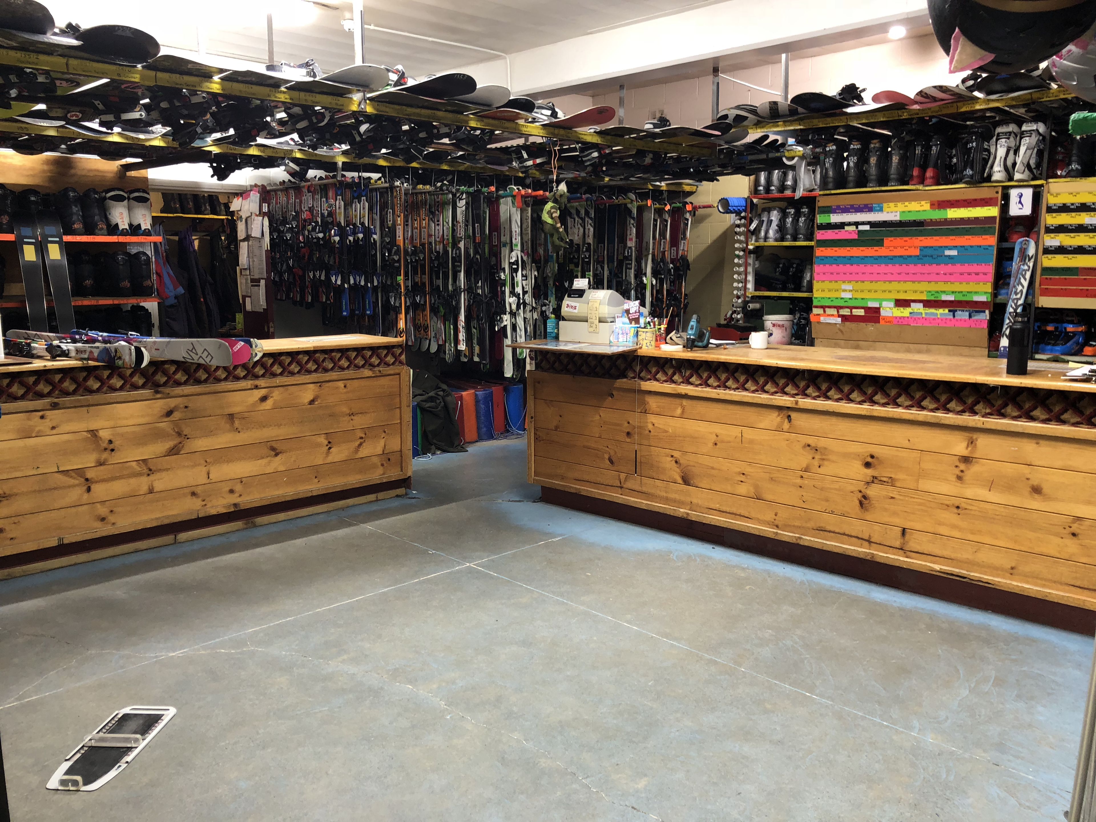 Tienda de equipo de esquí con mostradores de madera y estantes llenos de esquíes, botas y otros artículos.