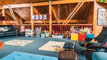 Relax and play in this inviting room with a tufted ottoman, leather armchair, and children's toys.