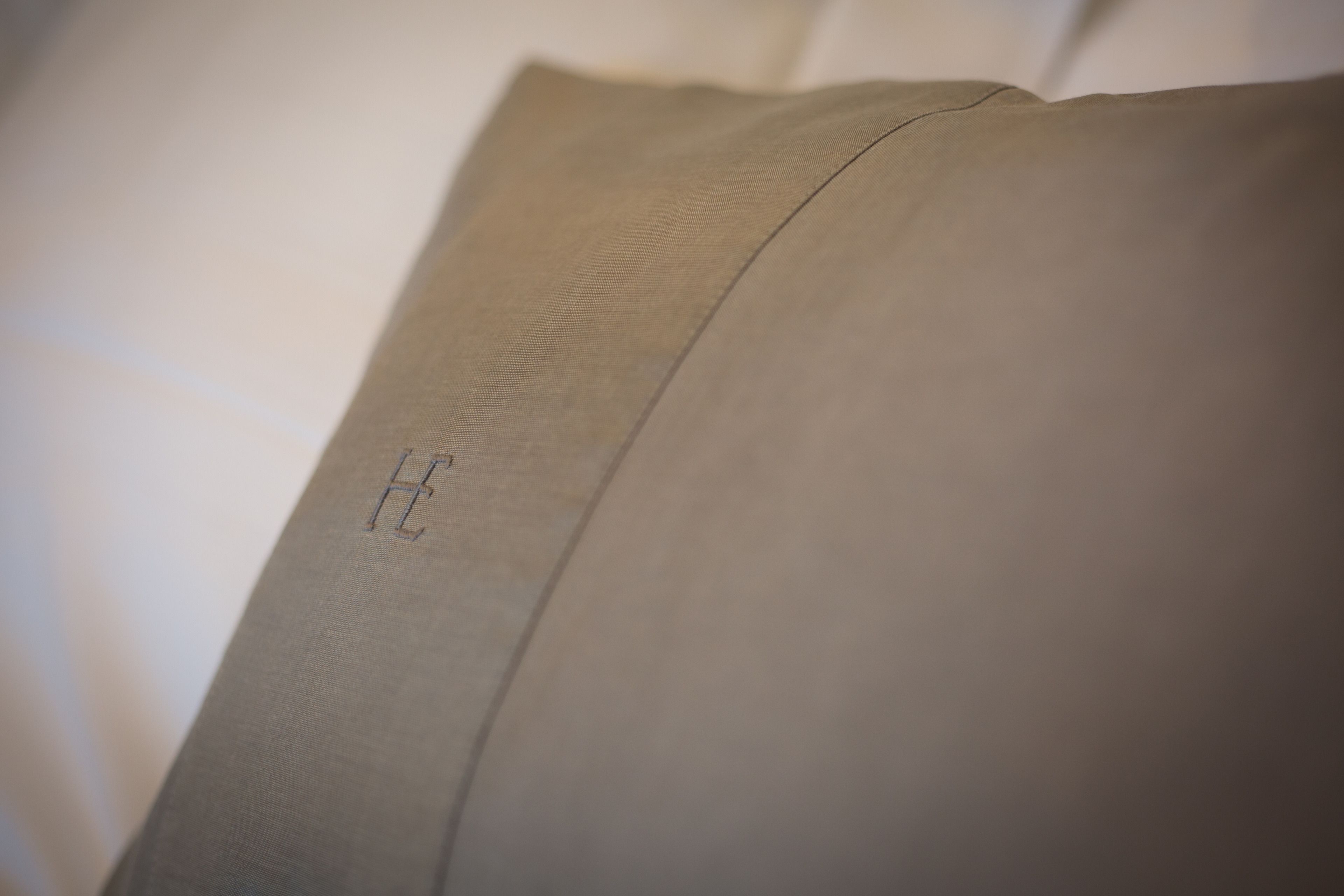 Primer plano de una almohada con una letra 'H' bordada a la vista.