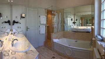Een moderne badkamer met dubbele wastafels, een grote spiegel, een douche met glazen wand en een losstaand bad.