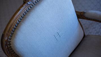 A close-up of a chair's backrest with a decorative edge and a visible embroidered letter.