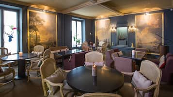 Un espace repas avec des tables rondes et des chaises en osier, agrémenté d’un centre de table composé de bougies.