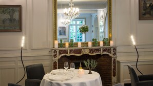 A dining room with a fireplace, a chandelier, and a table set for two. - Hotel d'Europe (Avignon)
