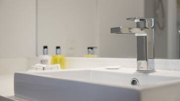 Un baño moderno con un grifo cromado, un lavabo blanco y un espejo que refleja la habitación.