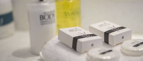 Un meuble-lavabo de salle de bain avec des articles de toilette, notamment un flacon de BOO, un flacon jaune et deux petites boîtes ornées d’un ruban noir.