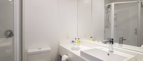Un baño moderno con lavamanos, espejo y retrete blancos.